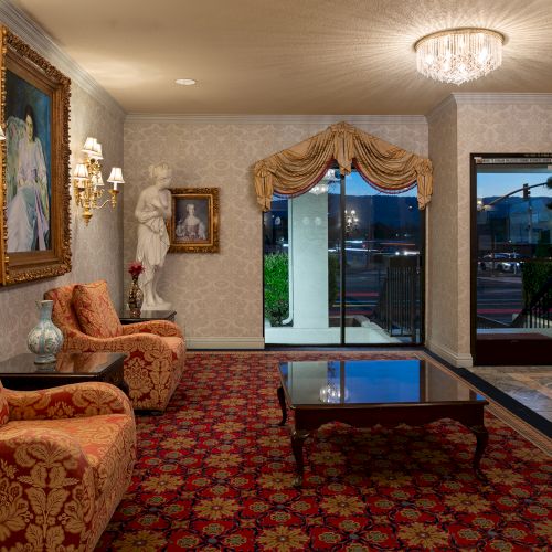 A cozy living room with warm lighting, a sofa, armchairs, a coffee table, and a TV area.