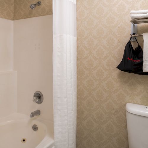 A bathroom door opens to a small tiled hallway with a mirror on the opposite wall and a glimpse of a countertop or sink on the right side.